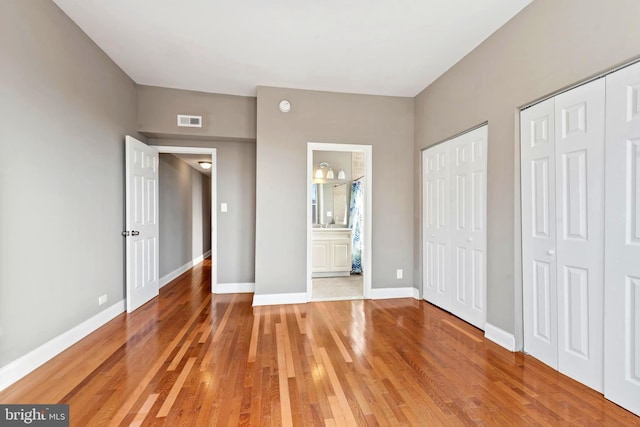 639 S Conkling St, Baltimore, MD 21224 - unfurnished bedroom with two closets, light wood-style floors, baseboards, and connected bathroom