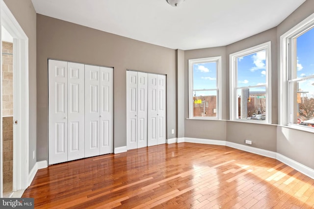 639 S Conkling St, Baltimore, MD 21224 - unfurnished bedroom featuring hardwood / wood-style floors, two closets, and multiple windows