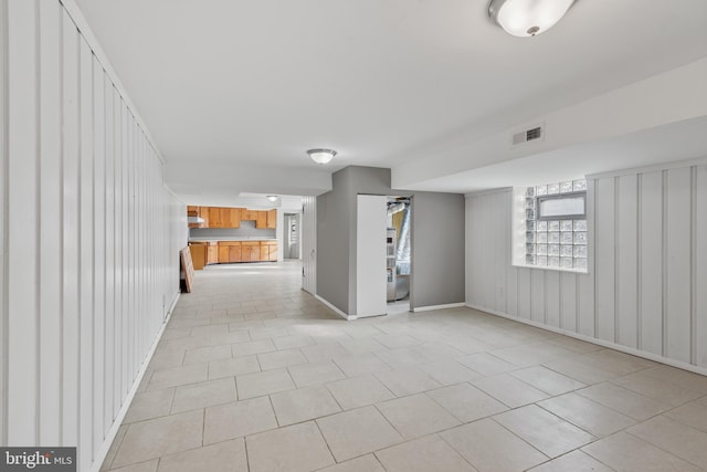 639 S Conkling St, Baltimore, MD 21224 - unfurnished living room with light tile patterned floors, baseboards, and wood walls