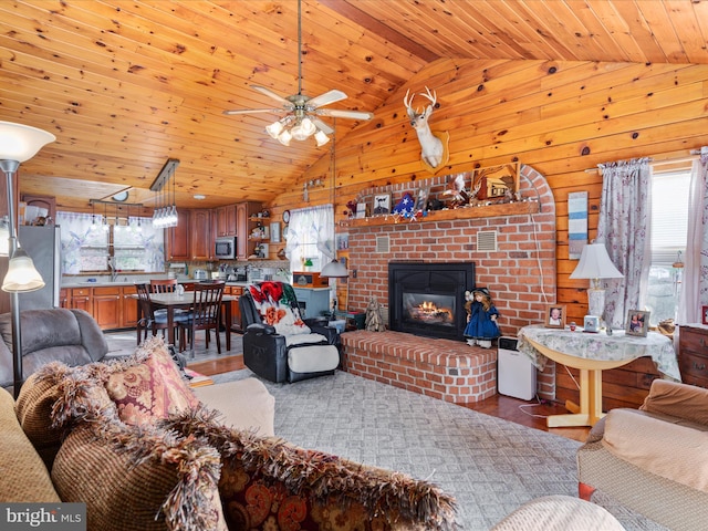 living room with wooden walls, plenty of natural light, wood ceiling, and a brick fireplace