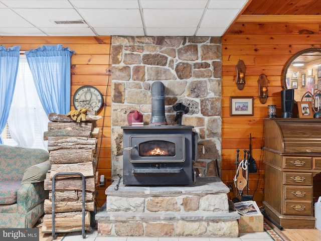 room details featuring a wood stove, a paneled ceiling, and hardwood / wood-style floors