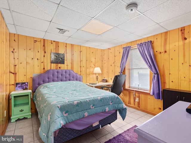 tiled bedroom featuring a drop ceiling and wood walls