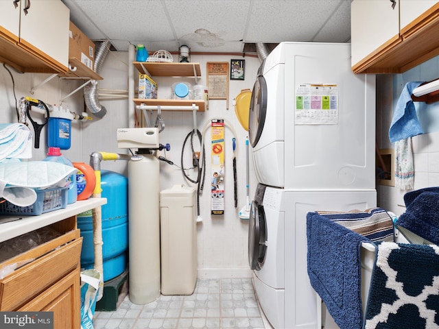 clothes washing area with cabinets and stacked washer / drying machine