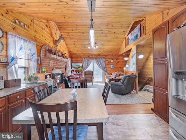 dining room featuring a wood stove, ceiling fan, wooden ceiling, vaulted ceiling, and wooden walls