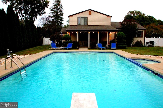 view of swimming pool with an in ground hot tub, a yard, a patio, and a diving board