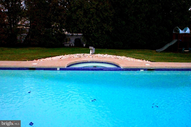 view of pool with an in ground hot tub and a lawn