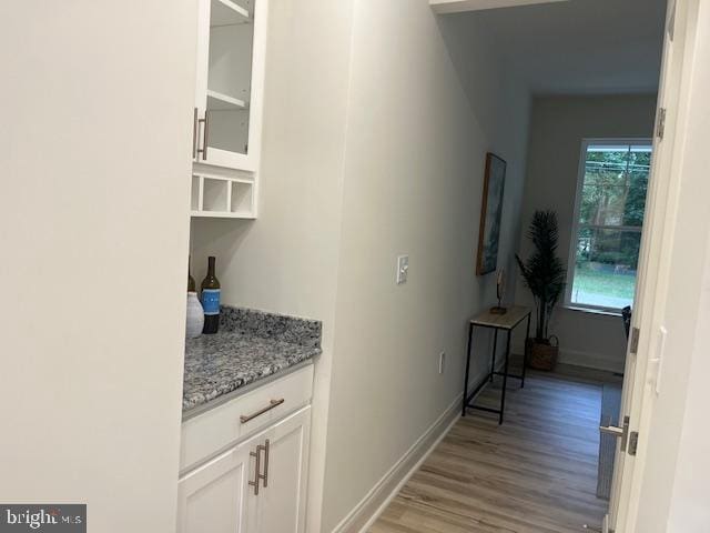 bar featuring light stone countertops, white cabinets, and light hardwood / wood-style floors