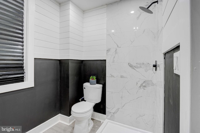 bathroom with a tile shower and toilet