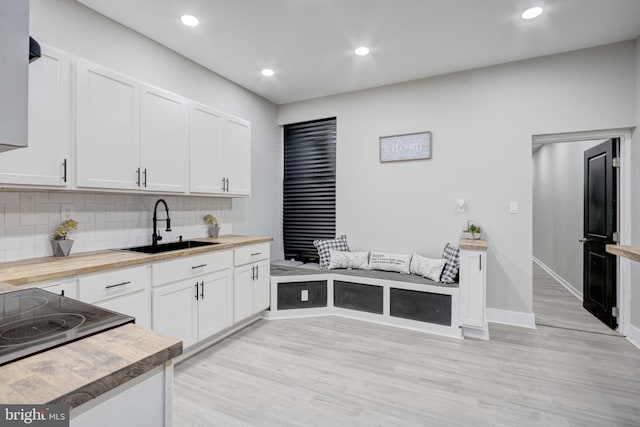 kitchen featuring white cabinets, butcher block counters, and sink