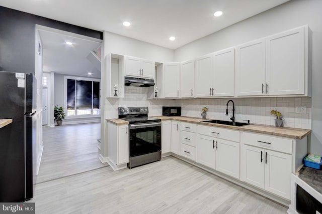 kitchen with black appliances, wood counters, white cabinets, and sink