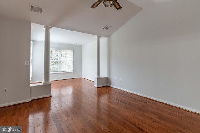 empty room with hardwood / wood-style floors, vaulted ceiling, ceiling fan, and ornate columns