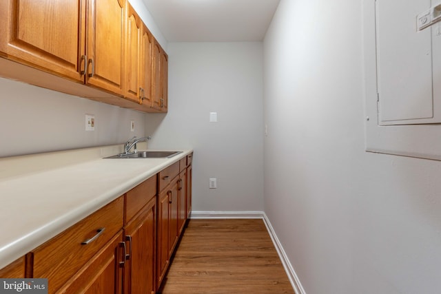 interior space with electric panel, light hardwood / wood-style floors, and sink