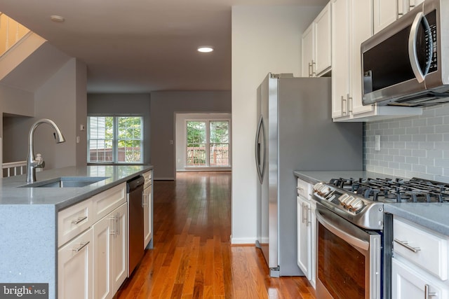 kitchen featuring light stone counters, stainless steel appliances, sink, hardwood / wood-style flooring, and white cabinetry