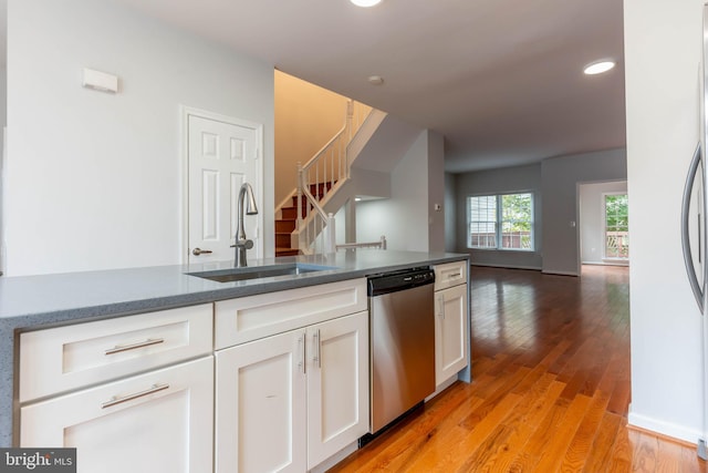 kitchen featuring sink, white cabinets, stainless steel dishwasher, and light hardwood / wood-style floors