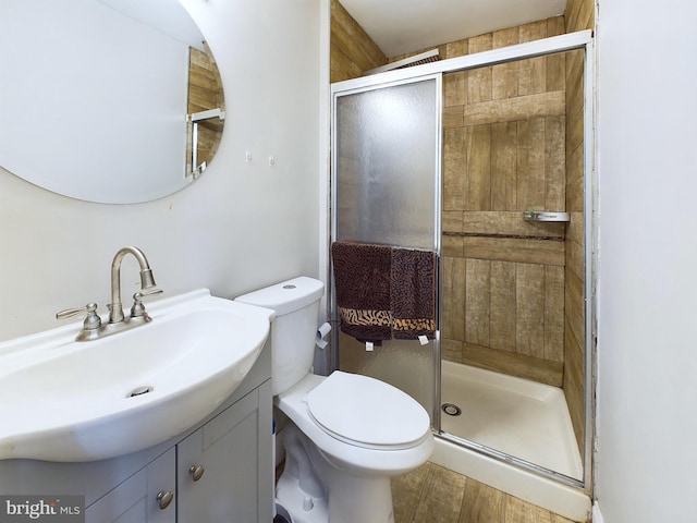 bathroom with hardwood / wood-style flooring, vanity, toilet, and a shower with shower door