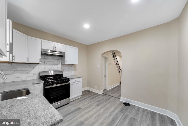 kitchen with white cabinets, light stone counters, stainless steel range with gas cooktop, and sink