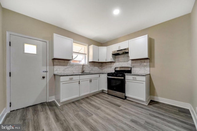 kitchen with decorative backsplash, sink, light hardwood / wood-style flooring, stainless steel gas stove, and white cabinetry