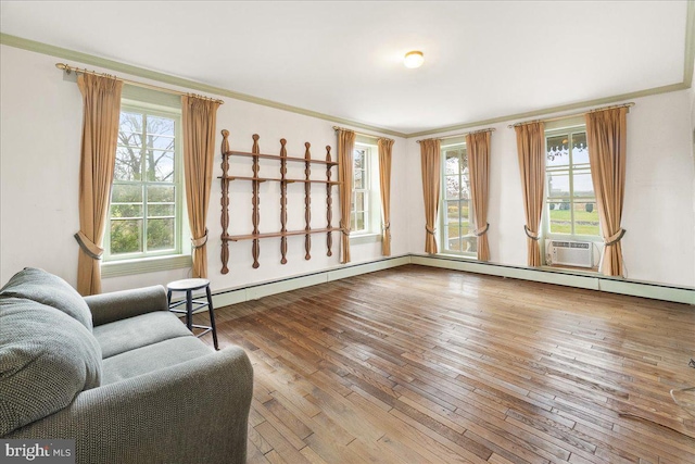 sitting room with wood-type flooring, a wealth of natural light, and ornamental molding