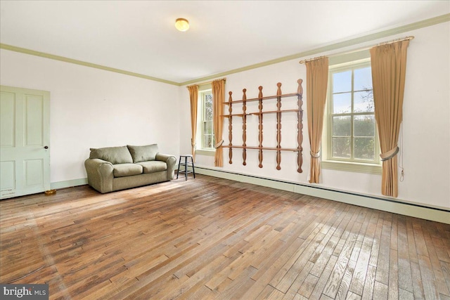 unfurnished living room with crown molding, wood-type flooring, and a baseboard heating unit