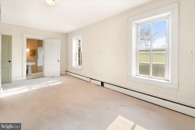 interior space featuring ensuite bathroom, light colored carpet, and a baseboard heating unit