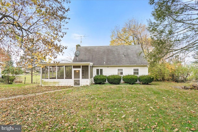 rear view of property featuring a lawn and a sunroom