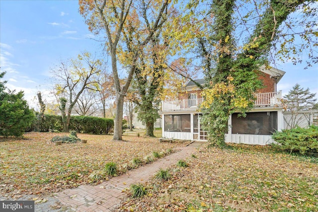 view of yard featuring a sunroom and a balcony