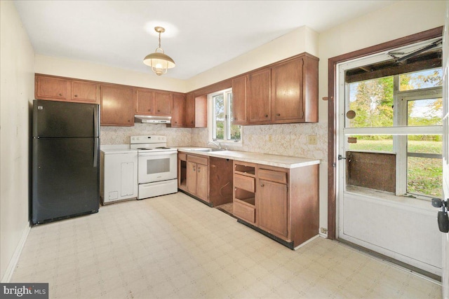 kitchen with backsplash, white range with electric cooktop, black refrigerator, sink, and hanging light fixtures