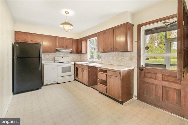 kitchen featuring decorative backsplash, black fridge, white range with electric stovetop, sink, and pendant lighting