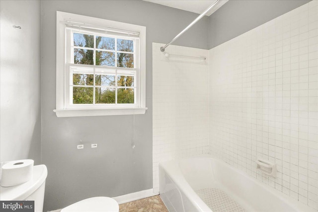 bathroom featuring tile patterned flooring, tiled shower / bath combo, and toilet