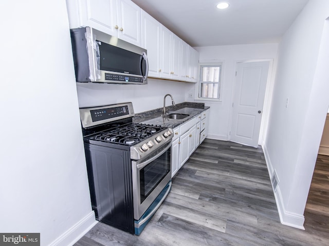 kitchen with appliances with stainless steel finishes, dark hardwood / wood-style floors, white cabinetry, and sink