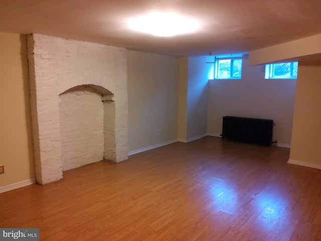 unfurnished room featuring radiator heating unit and hardwood / wood-style flooring