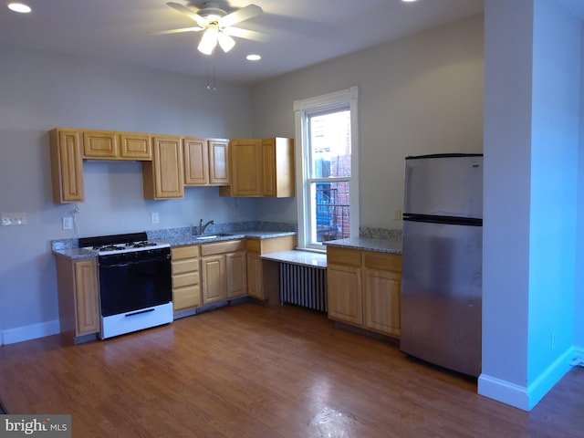 kitchen featuring gas range, radiator heating unit, stainless steel refrigerator, and dark wood-type flooring