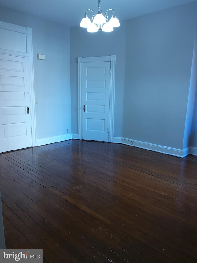 unfurnished room featuring dark wood-type flooring and a chandelier