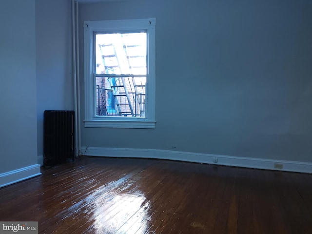 unfurnished room featuring dark hardwood / wood-style flooring and radiator heating unit