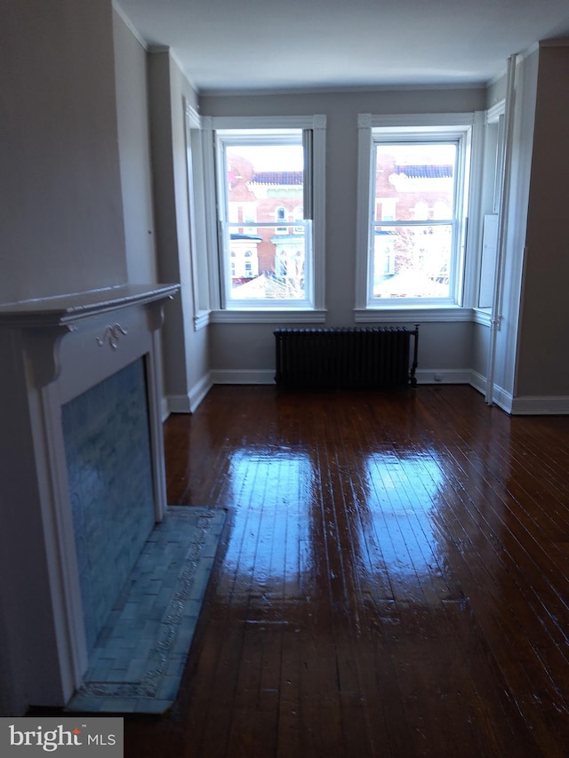 unfurnished living room featuring radiator, a healthy amount of sunlight, and dark hardwood / wood-style floors