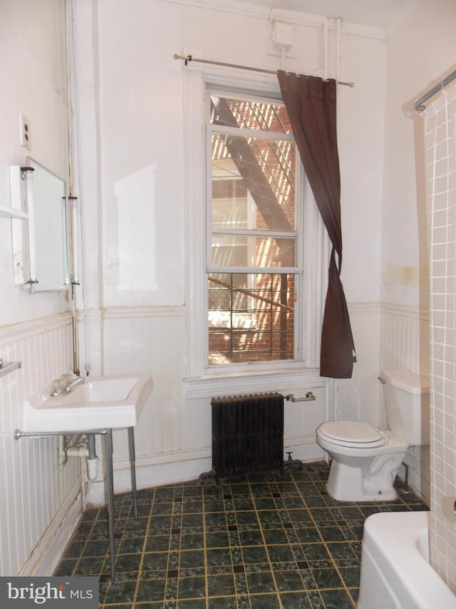 bathroom with a bathtub, toilet, radiator heating unit, and sink