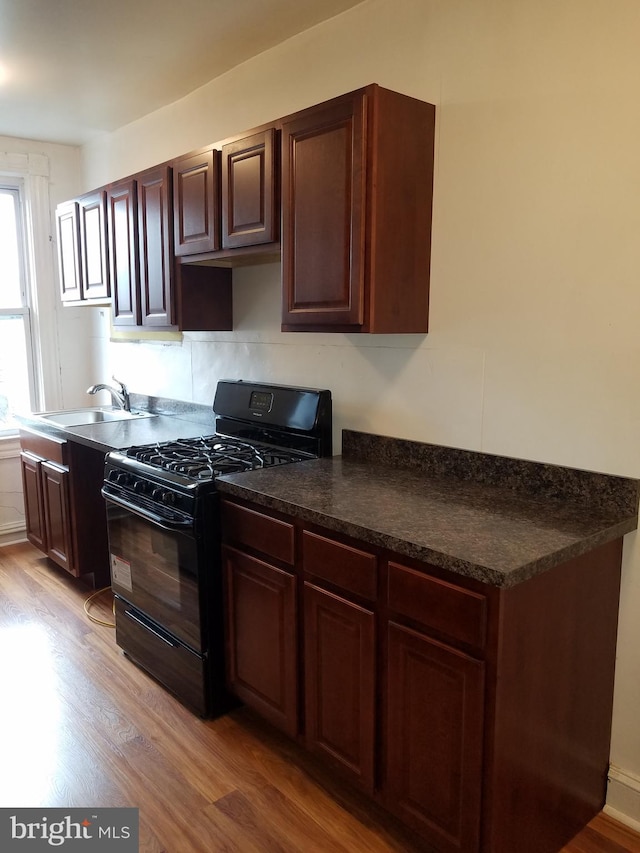 kitchen with black range with gas stovetop, dark brown cabinetry, sink, and light wood-type flooring