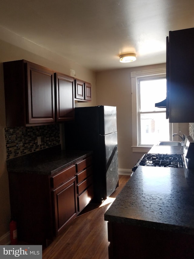 kitchen with stove, sink, dark hardwood / wood-style floors, decorative backsplash, and dark brown cabinetry