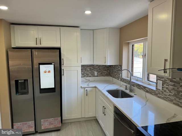 kitchen featuring white cabinetry, sink, stainless steel appliances, and light stone counters