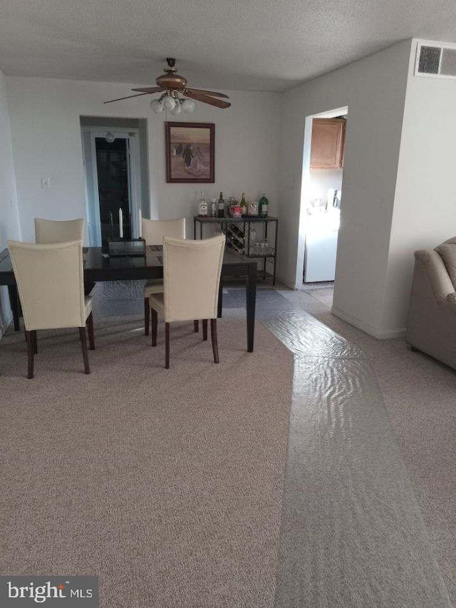 carpeted dining area featuring ceiling fan, washer / dryer, and a textured ceiling