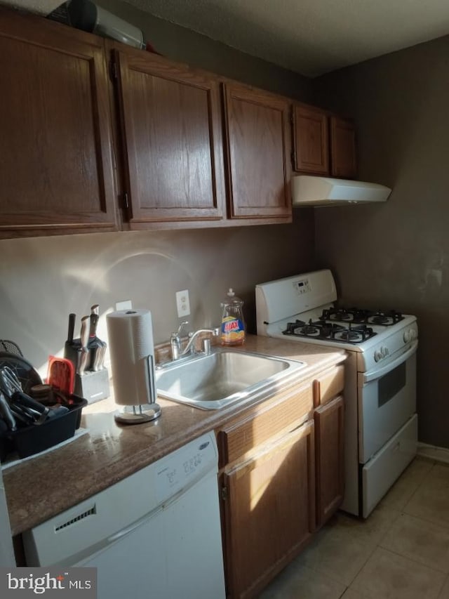 kitchen featuring sink, light tile patterned flooring, and white appliances