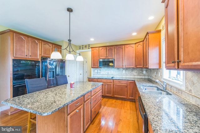 kitchen with sink, hanging light fixtures, light hardwood / wood-style floors, a breakfast bar, and appliances with stainless steel finishes