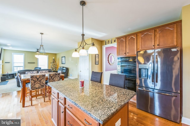 kitchen with stainless steel fridge with ice dispenser, a center island, hanging light fixtures, and light hardwood / wood-style floors