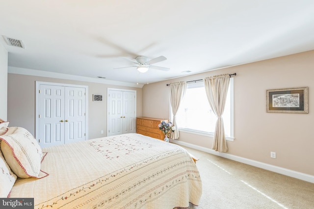 carpeted bedroom featuring ceiling fan and multiple closets