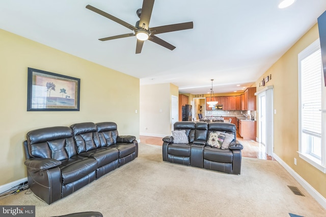 carpeted living room with ceiling fan