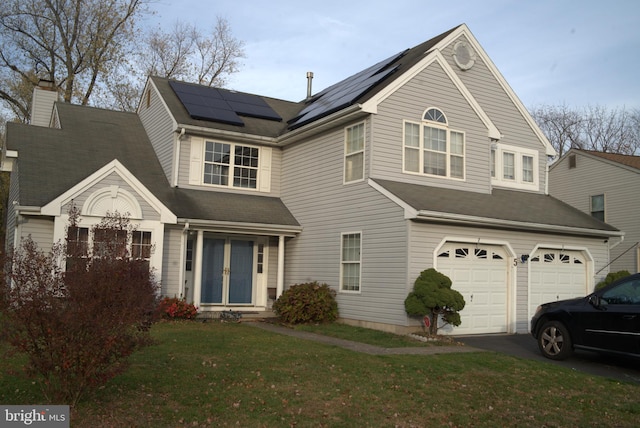 view of front of property featuring solar panels, a garage, and a front lawn