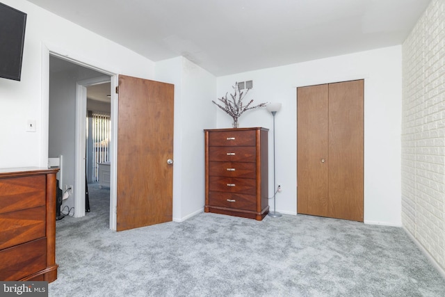 carpeted bedroom with brick wall and a closet