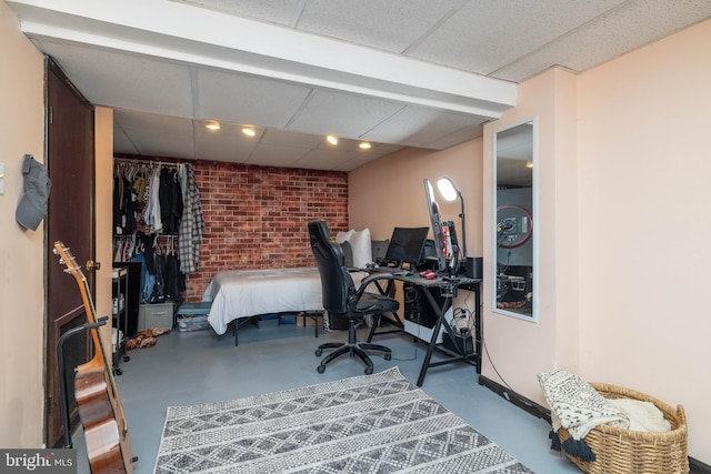 bedroom featuring a drop ceiling and concrete floors