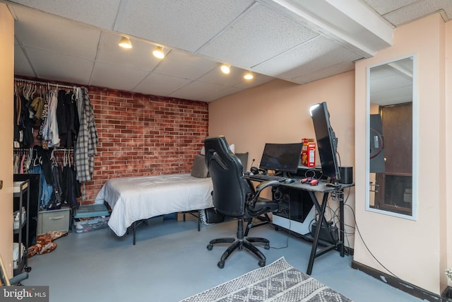 bedroom featuring concrete flooring and a paneled ceiling