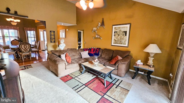 living room with vaulted ceiling, hardwood / wood-style floors, and ceiling fan with notable chandelier